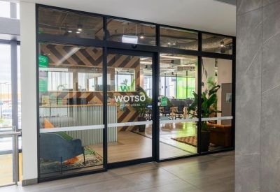 Glass entrance doors with WOTSO branding leading into a modern reception and lounge area.
