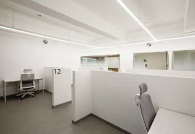 Open-plan office with white desk pods and linear ceiling lights.