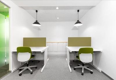 Symmetrical two-person workspace with white desks, green chairs, and pendant lighting.
