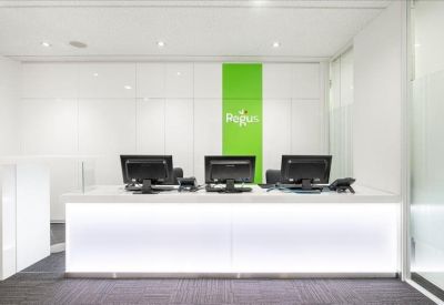 Modern white reception desk with a vibrant green feature wall and digital branding.