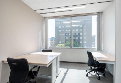 Bright private office suite with two desks and a large window overlooking the city.