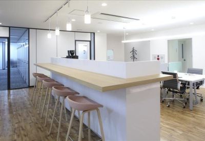 Communal break area with a long wooden counter and pink bar stools.