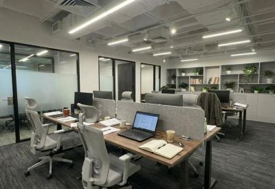 Modern open-plan office with multiple workstations and bright overhead lighting.