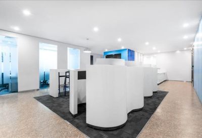 Modern coworking area with curved white privacy pods on a dark grey rug.
