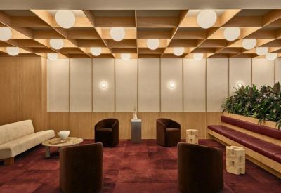 Stylish lounge area with velvet armchairs, a red carpet, and a decorative timber ceiling.