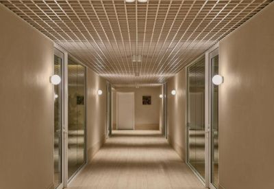 Symmetrical office corridor with warm lighting and a modern grid ceiling.