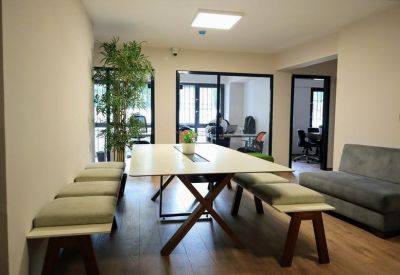 Communal break area featuring a long wooden table with benches and a tall indoor plant.