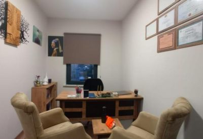 Private office suite with a wooden desk, armchairs, and framed certificates on the wall.