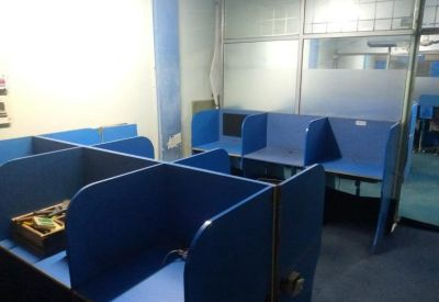 L-shaped blue office cubicles partitioned by glass walls.