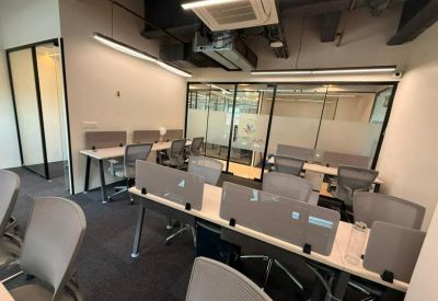 Open coworking space with glass-partitioned offices and linear overhead lighting.