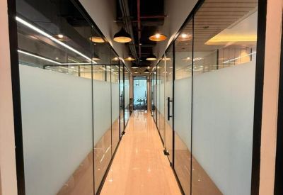 Long bright hallway with polished floors and glass-walled private offices on both sides.