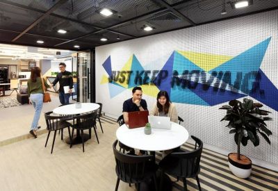 Bright breakout space featuring a colorful geometric wall mural and circular white meeting tables.