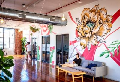 Open-plan lobby featuring a large floral mural on a white wall and polished timber floors.