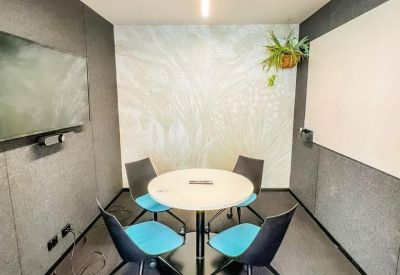 Small meeting room with a round table, four blue chairs, and a feature wall mural.
