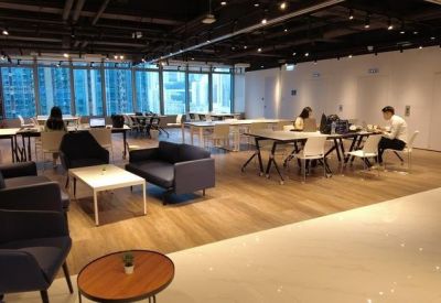 Spacious communal lounge with dark sofas, coffee tables, and wood-look flooring.