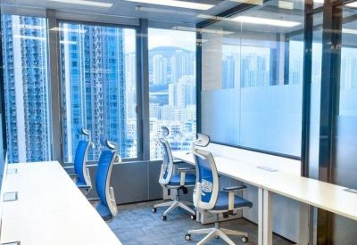 Bright shared office space with blue ergonomic chairs and views of neighboring skyscrapers.