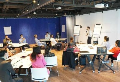 Large meeting room with several people participating in a workshop with flipcharts.