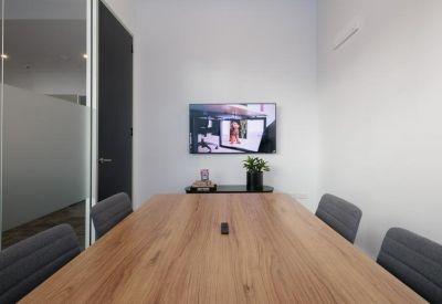 A professional meeting room featuring a wooden table and a wall-mounted TV.