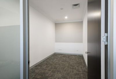 A minimalist internal private office with grey carpeting and white walls.