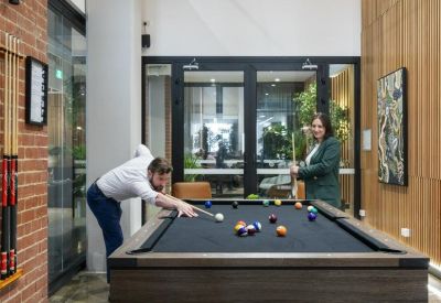 Common area featuring a full-sized billiards table set against a classic red brick wall.