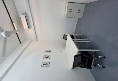 Compact private office with a white desk, black ergonomic chairs, and wall art.