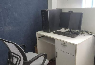 Single-person office workstation with a white desk, computer, and ergonomic mesh chair.