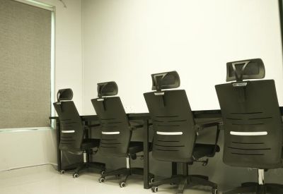 Row of black ergonomic office chairs at a long shared workstation.