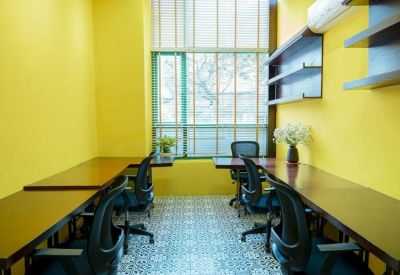 Bright private office featuring yellow walls and two wooden desks with ergonomic black chairs.