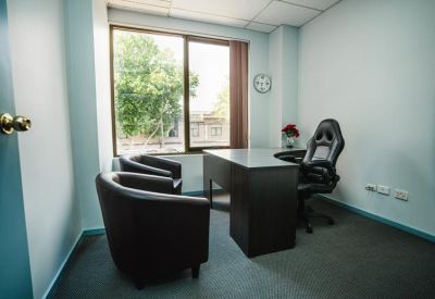 Minimalist private office with a corner desk and views of greenery.