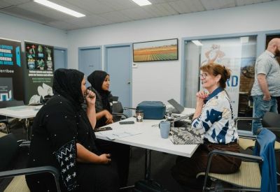 Coworking space where people of diverse backgrounds are seated around a white table for a meeting.