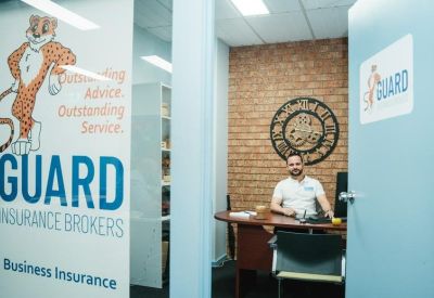 Private office entrance featuring a glass door with insurance broker branding and a brick wall.