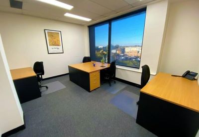 Private three-person office suite with wooden desks and a large window.