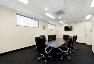 Professional boardroom with a dark table, leather chairs, and wall-mounted TV.