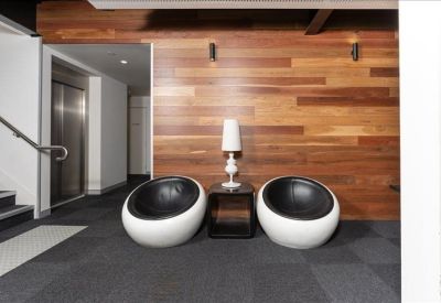 Reception waiting area with two white sphere chairs and a warm wood-paneled wall.