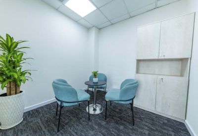 Small meeting nook with blue velvet chairs and a minimalist round table.