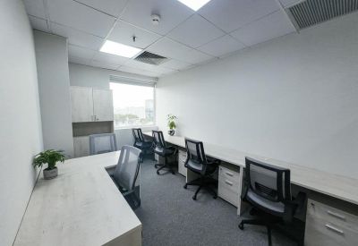 Bright office space with multiple white desks and ergonomic black chairs.