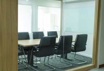 Professional meeting room seen through a glass partition with black leather chairs.
