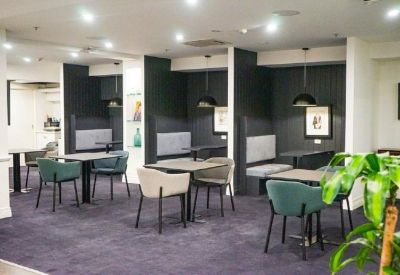 Quiet coworking zone with semi-private booths and small dining tables.
