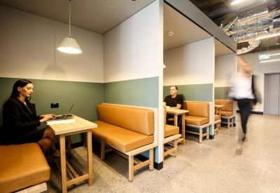 Individual booth seating with leather benches and green feature walls.