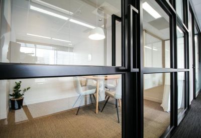 Private meeting room viewed through black-framed glass doors.