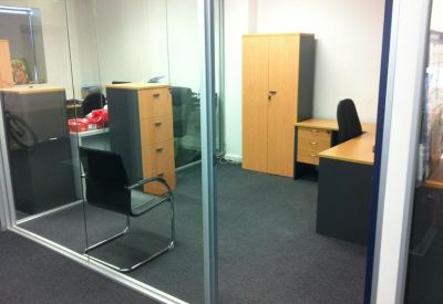 Private office suite with a wooden desk, storage cabinets, and a black mesh chair.