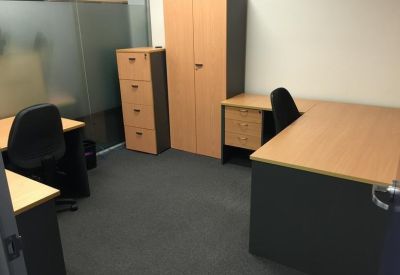 Compact office workstation with a wooden desk, file cabinet, and tall storage cupboard.