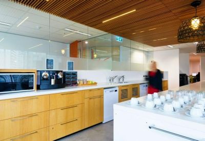 Sleek office kitchen and coffee station with light wood cabinetry.