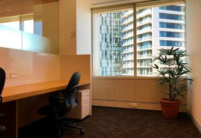 Private office workstation with a black ergonomic chair and large window.