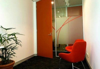 Small meeting room or consultation space with bright orange chairs.