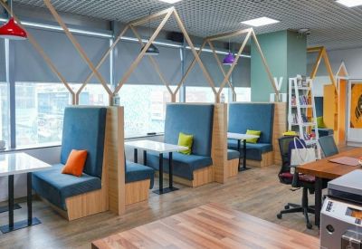Modern office booths with blue upholstery, orange pillows, and wooden partitions.