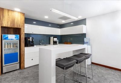Bright communal kitchen area with a high white breakfast bar and stools.