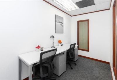 Compact two-person private office with white desks and mesh chairs.