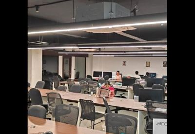 Shared office space featuring long wooden-topped desks and comfortable mesh chairs.