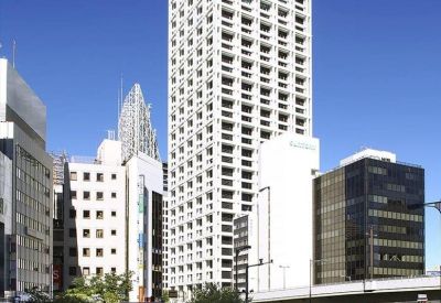 Modern conference room with a long dark wood table, leather chairs, and a sleek black feature wall.